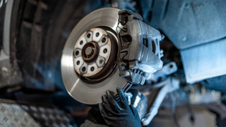 Mechanic inspecting the brake rotors and pads of a car