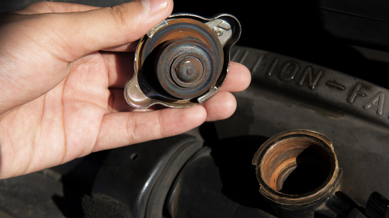 person holding a rusty radiator cap