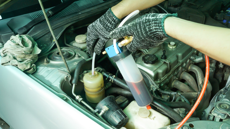 Mechanic using an extractor pump to remove the old power steering fluid