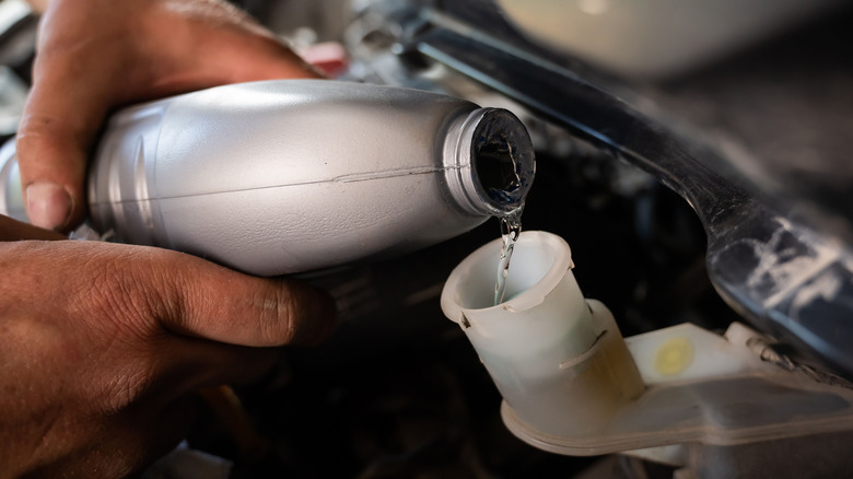 Mechanic pouring fresh brake fluid into the reservoir