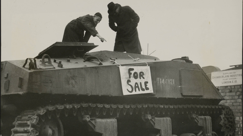 A black and white image of a Sherman tank for sale and being inspected