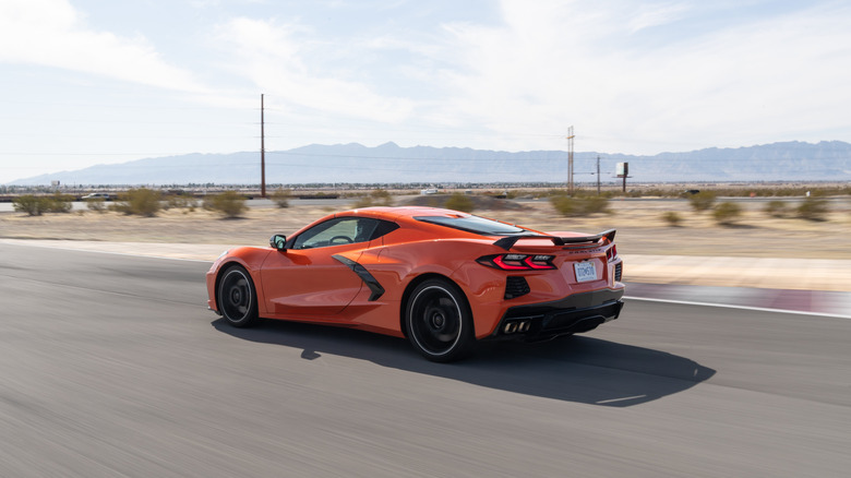 A rear 3/4 shot of an orange 2020 Chevrolet Corvette Stingray on the road in front of a desert background