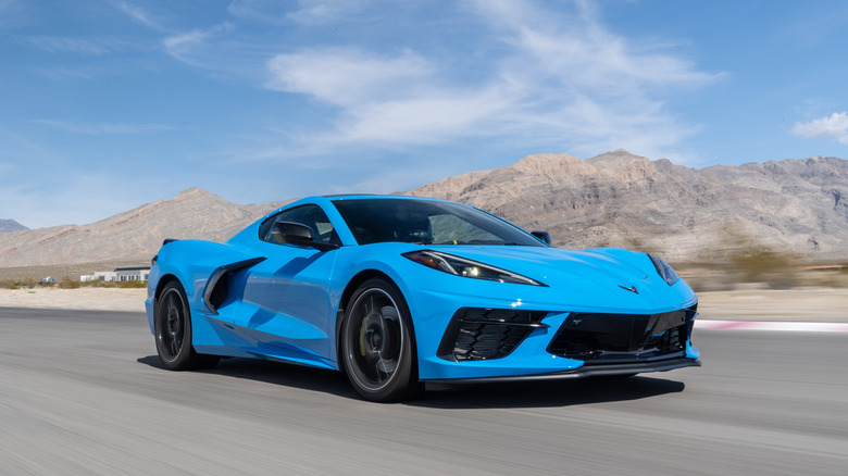 A front 3/4 shot of a blue 2020 Chevrolet Corvette Stingray on a road in front of rocky desert mountains