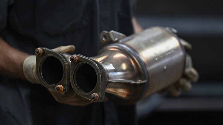 a mechanic holding a catalytic converter