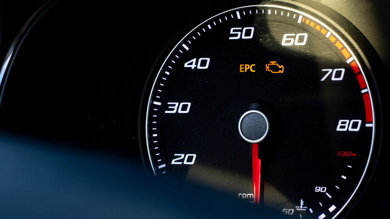 An illuminated check engine warning lamp on a car dashboard.