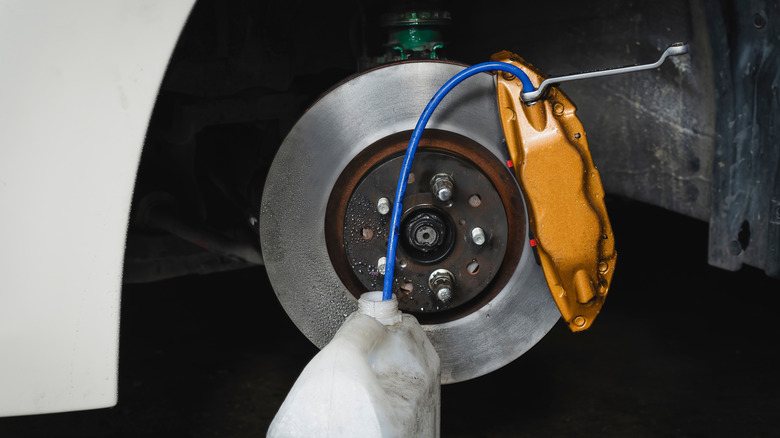 Bleeding a corner of a vehicle's brake caliper during a brake bleed job, with copper brake caliper prominently displayed.