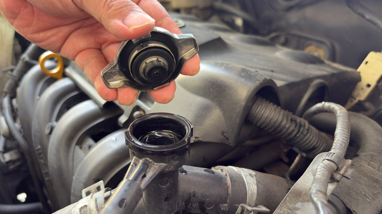 A driver holding their radiator cap