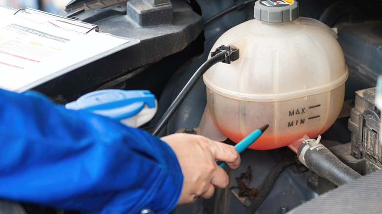 A technician inspecting a coolant reservoir