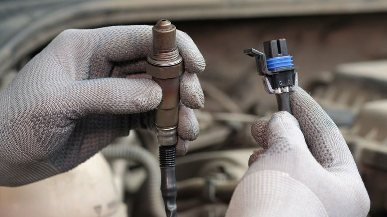 A mechanic's hands holding oxygen sensor for car