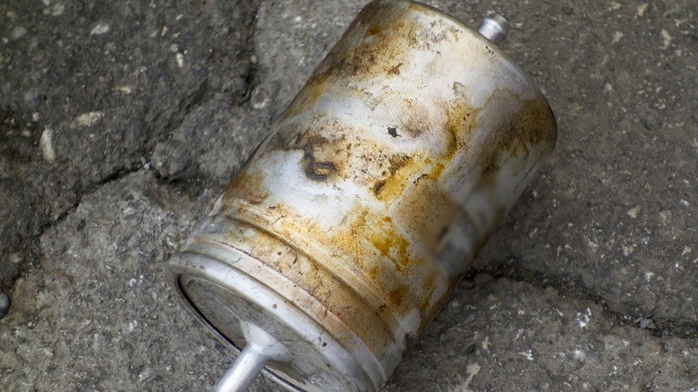 Dirty used fuel filter lying on ground