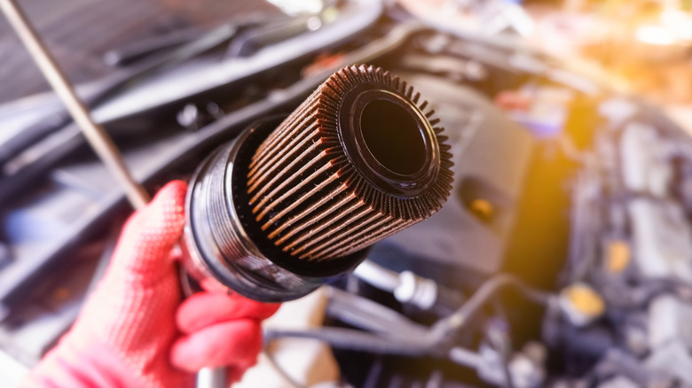 Gloved hand holding a car fuel filter
