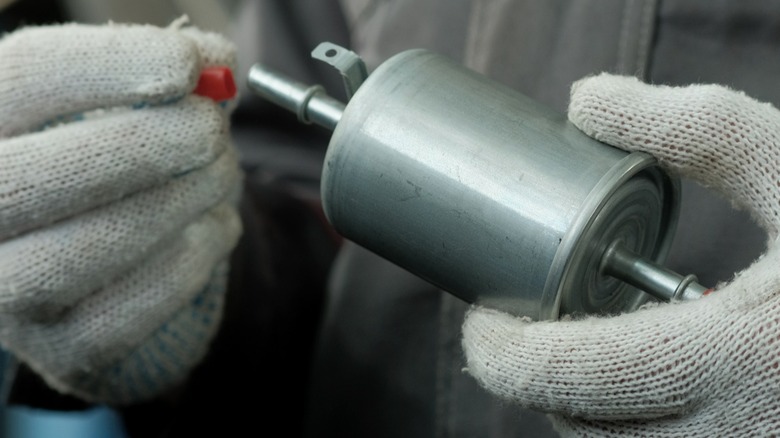 A mechanic holds a new fuel filter