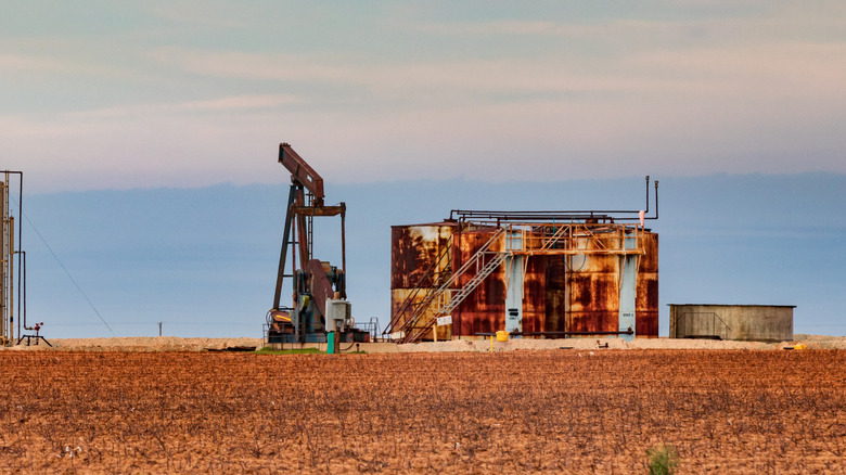 An abandoned oil rig and tanks, rusted in the middle of the desert.
