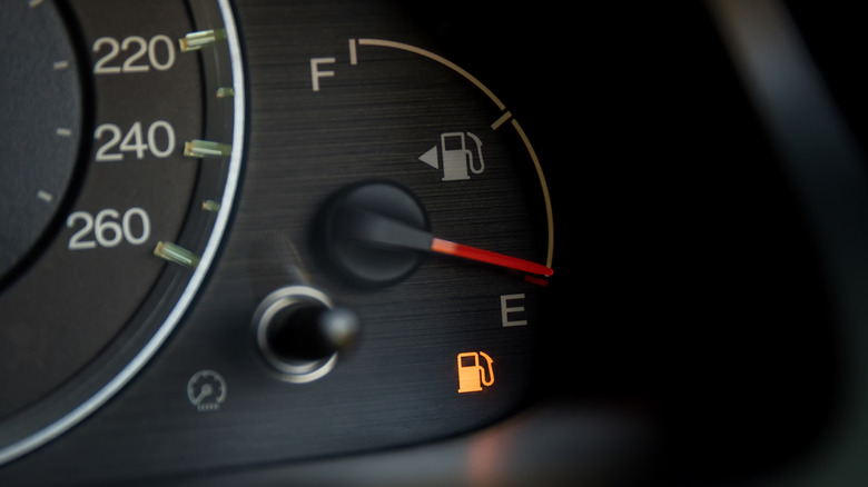 A closeup view of a fuel gauge on empty with a low-fuel light