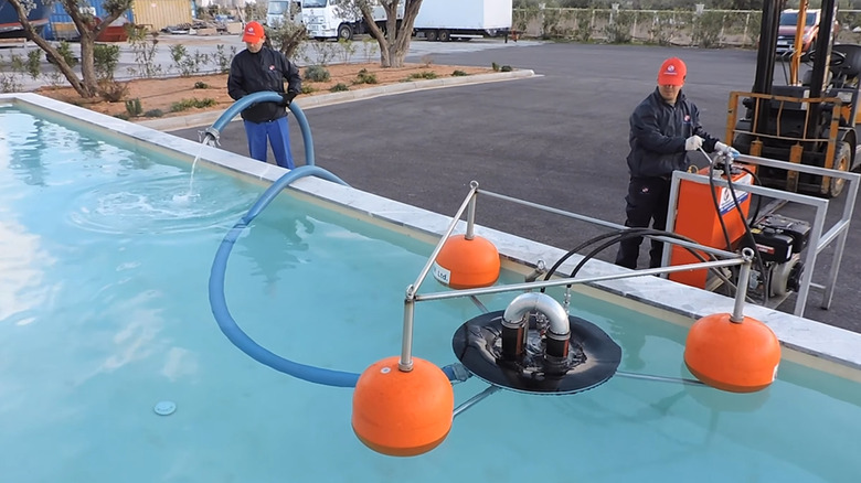 A pair of workers testing an oil spill skimmer in a pool of water