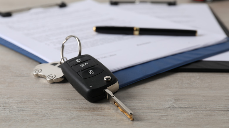 Olovka, ključ od automobila i međuspremnik s dokumentima na stolu.