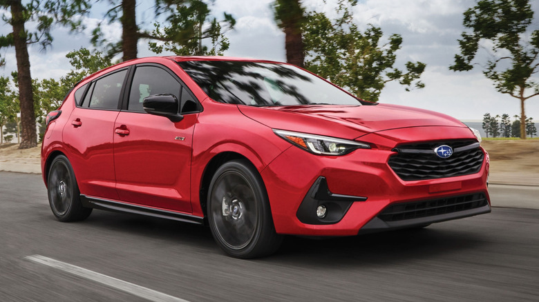 2025 Subaru Impreza driving down a road with trees in the background