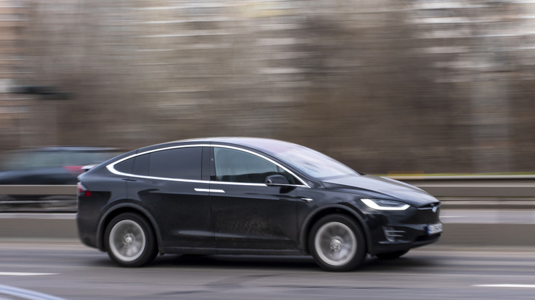 A black Tesla Model X moving swiftly on the highway