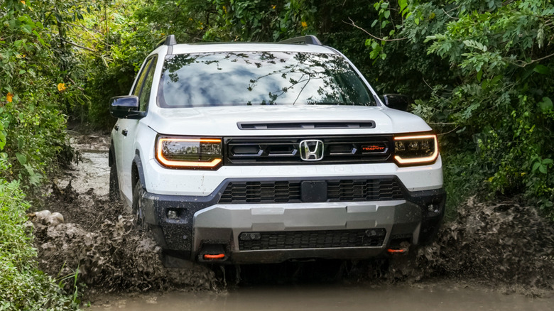 Front view of 2026 Honda Passport TrailSport splashing through muddy stream