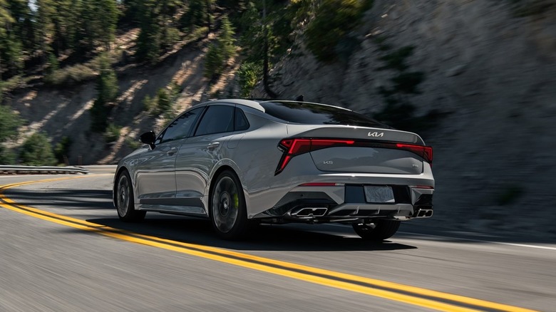 Rear-quarter view of a gray 2025 Kia K5 on the road