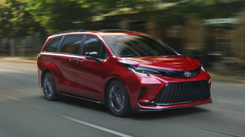 Red 2026 Toyota Sienna XSE driving down city street with buildings in the background