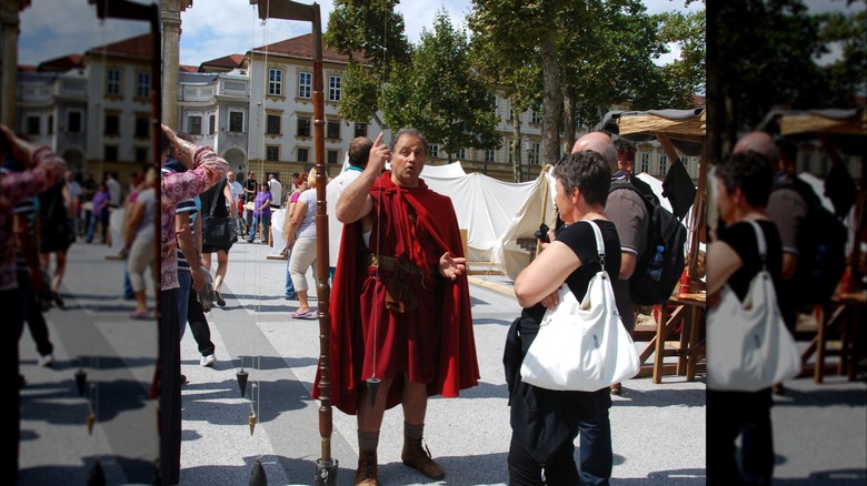A man dressed in ancient Roman garb pointing at a groma.