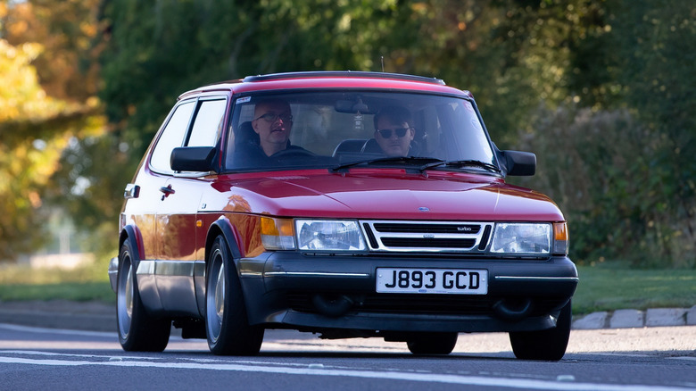 A red Saab 900 Turbo cruising along, looking good as ever against an Autumn setting.