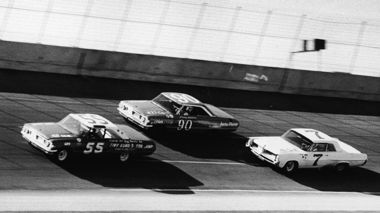 NASCAR in the early 1960s. Three cars are bunched up on a racetrack.