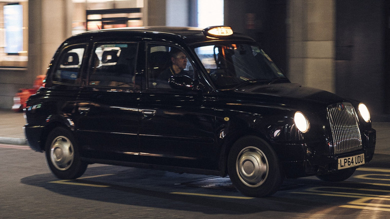 A black TX4 London taxicab driving at night.