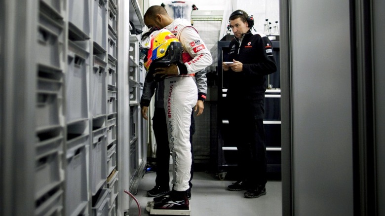 F1 driver Lewis Hamilton being weighed before the 2012 Shanghai Grand Prix.