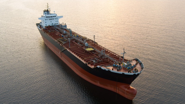 A large orange and black oil tanker on a calm ocean