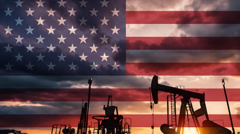 An oil well with American flag and the setting sun in the background