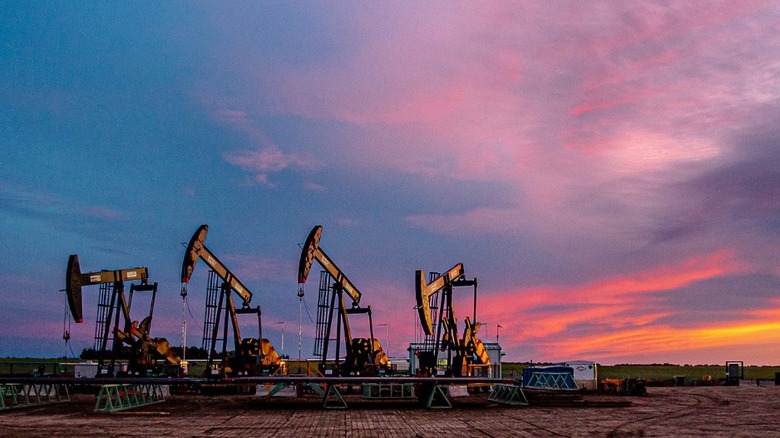 An oil field with four wells and a sunset in the background