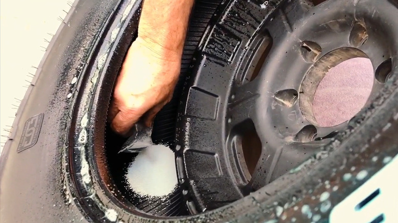 Pouring tire balancing beads inside the tire