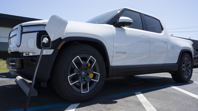 A white Rivian charging at a charging station.