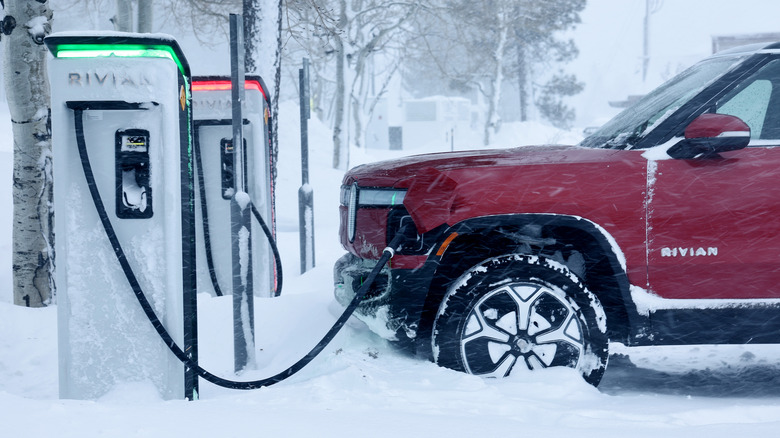 A red Rivian R1S charging in the snow.