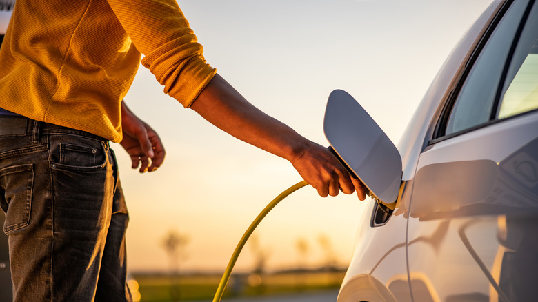 A person plugging in a plug-in hybrid vehicle.