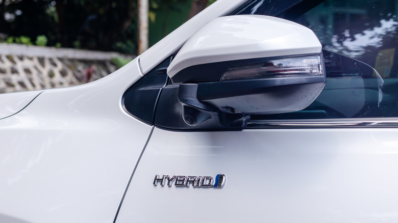 A white hybrid vehicle with a hybrid badge on the side of it.