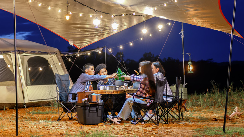 A group of young people camping with electricity out in the wilderness.
