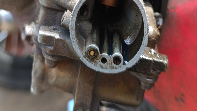 Cleaning a carburetor on an engine.