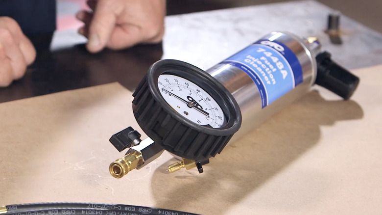An OTC Fuel Injection cleaner 7448A laying on a table with the pressure gauge in focus.