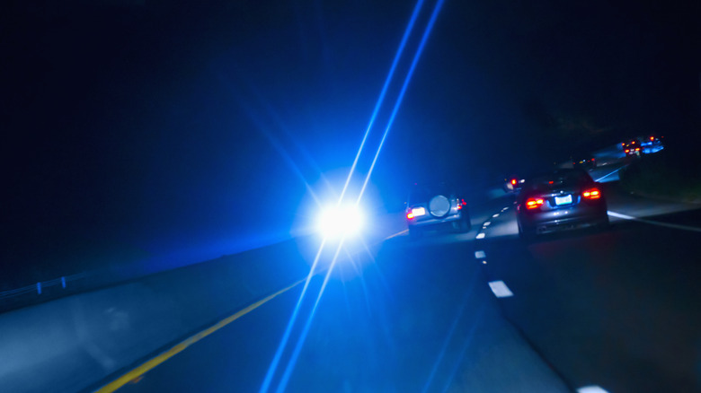 The view of a freeway at night with an oncoming car blinding the camera