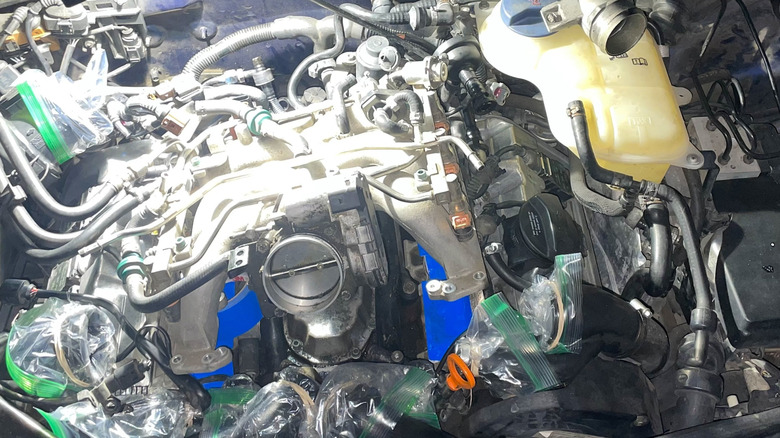 Removing the intake manifold from a B5-generation Audi S4, with coolant and intake piping sealed.