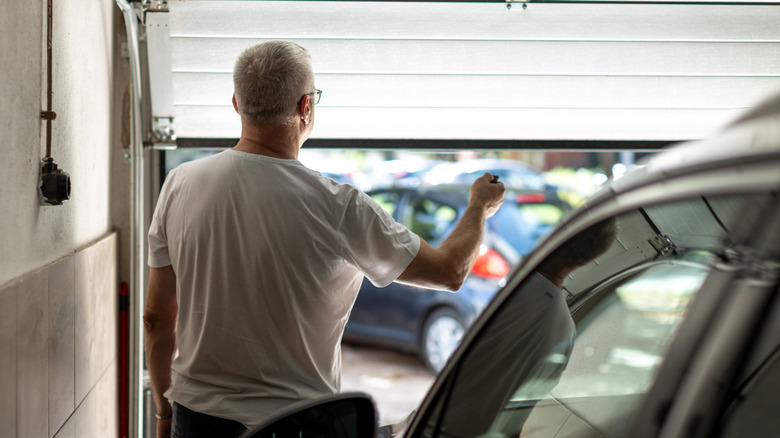 A man opening a garage door with a remote