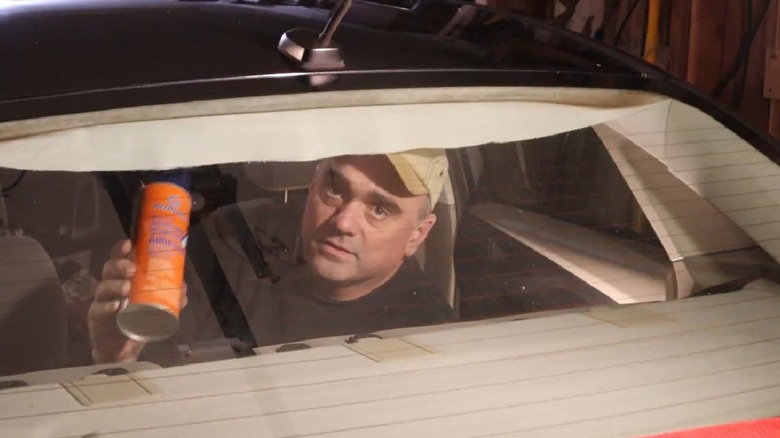 A man about to use spray adhesive to fix a sagging headliner