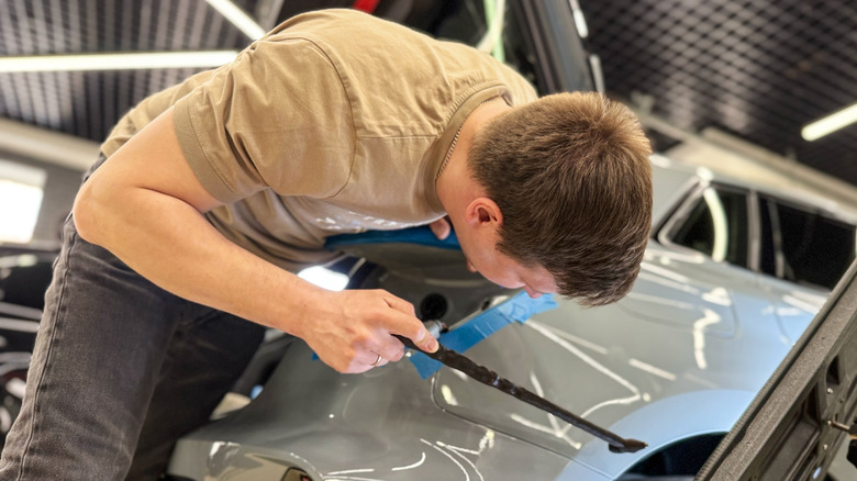 A man fixing a dent on car by hand