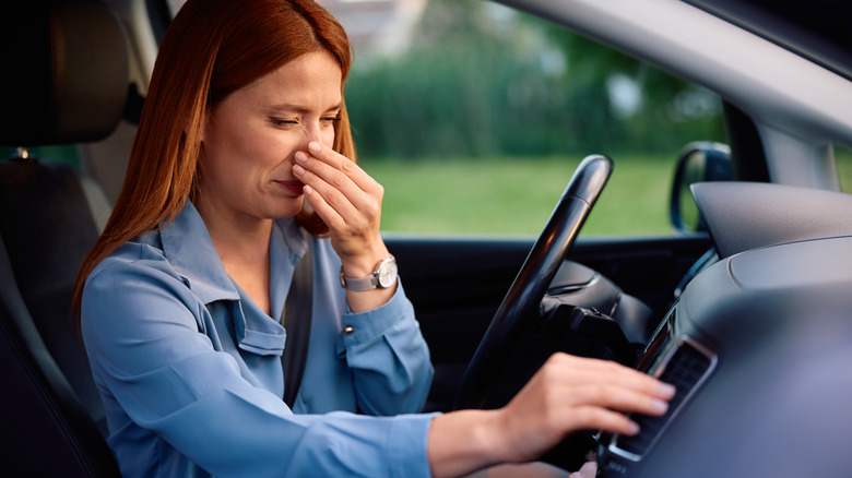 A female driver reacting to the bad AC smell of the car