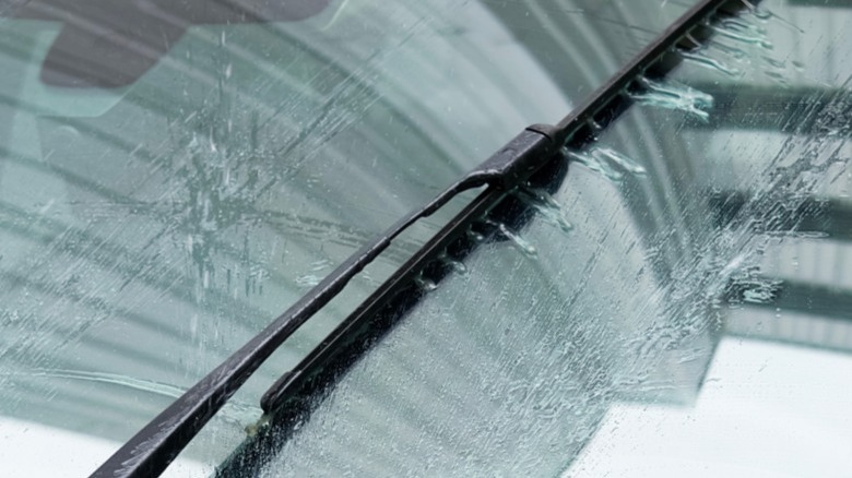 A properly working windshield washer nozzle dispensing fluid on a car's windshield.