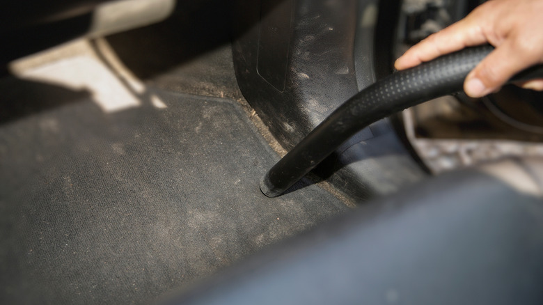 Man utilizing a vacuum cleaner to cleanable car carpets