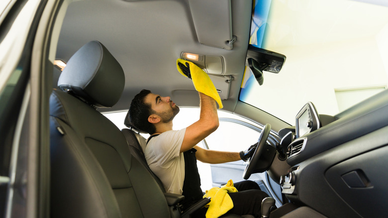 Man cleaning the headliner of a car